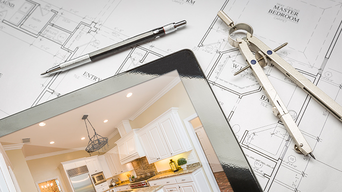Tablet mit Wohnraumfoto, umgeben von Bauplänen und Zeichenwerkzeug für Architektur und Bauwesen.