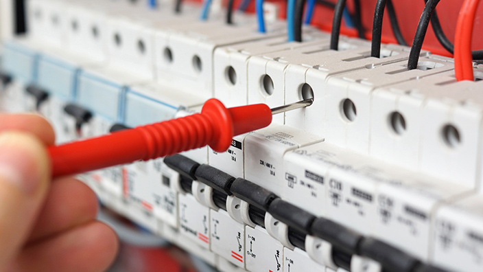 Nahaufnahme eines elektrischen Schalttafels mit Messgerät, repräsentiert Energie- und Elektrotechnik.