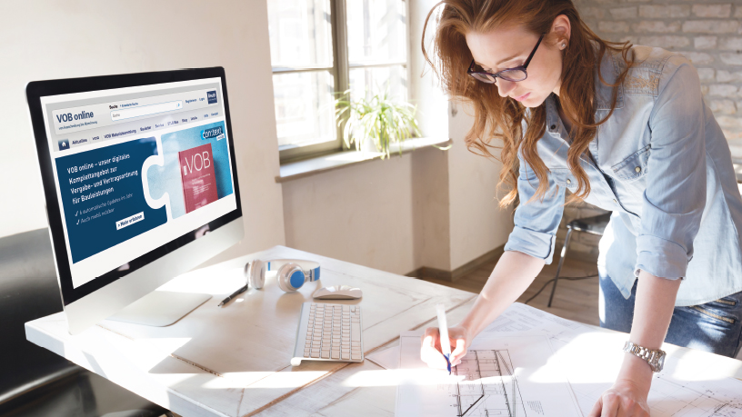 Architektin arbeitet an Bauplänen, Computermonitor zeigt VOB Online Webseite