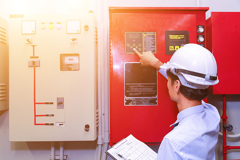 Ingenieur mit Schutzhelm überprüft ein Steuerpanel.
