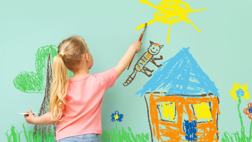 Kind malt bunte Zeichnung von Haus und Sonne, symbolisiert kreative Vorstellung von energieeffizenten Gebäuden.