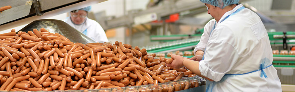 Würste werden in einer Lebensmittelproduktionsanlage verarbeitet und verpackt.