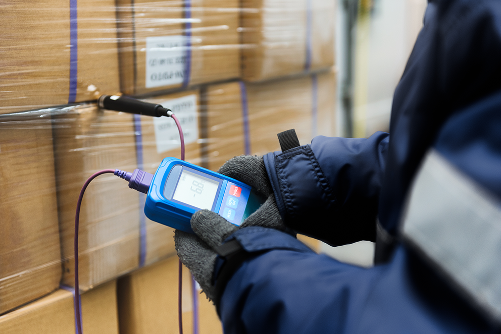 Eine Person prüft die Temperatur von verpackten Waren mit einem digitalen Thermometer.