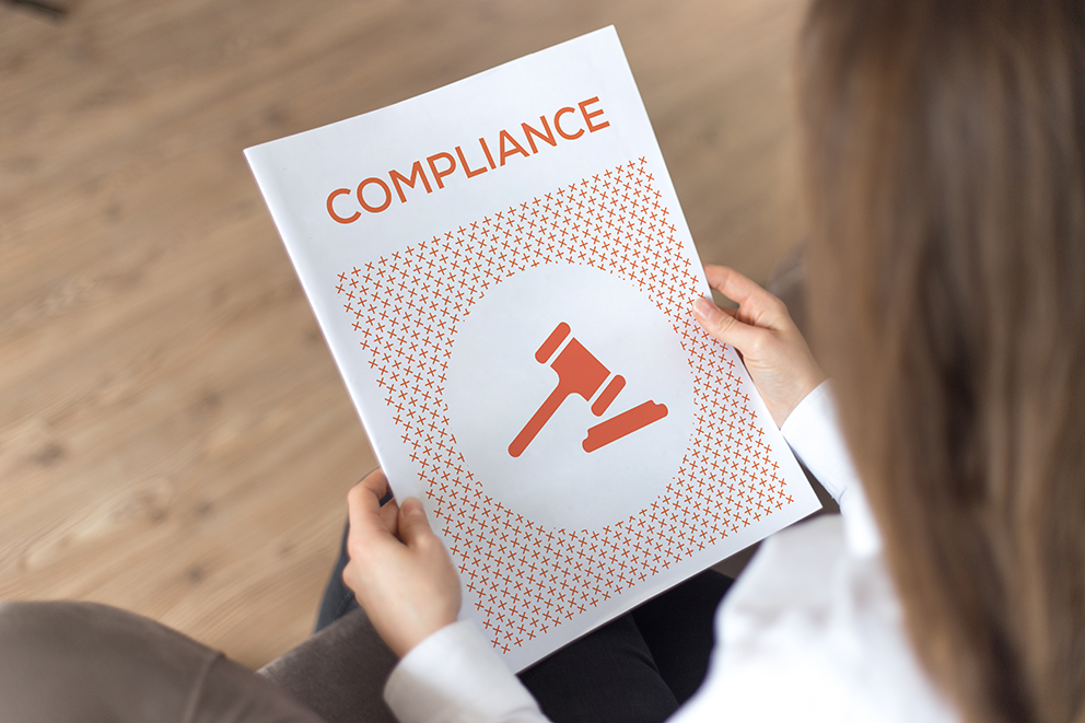 Person hält ein Compliance-Dokument mit einem Richterhammer-Symbol.