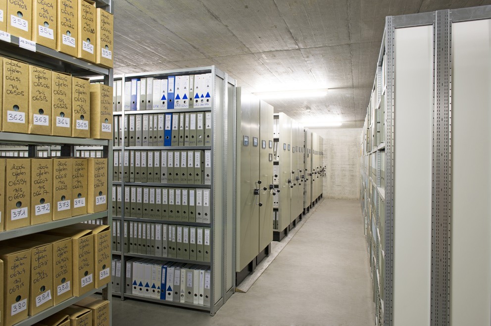 Archivraum mit Regalen voller Aktenordner und Kartons.