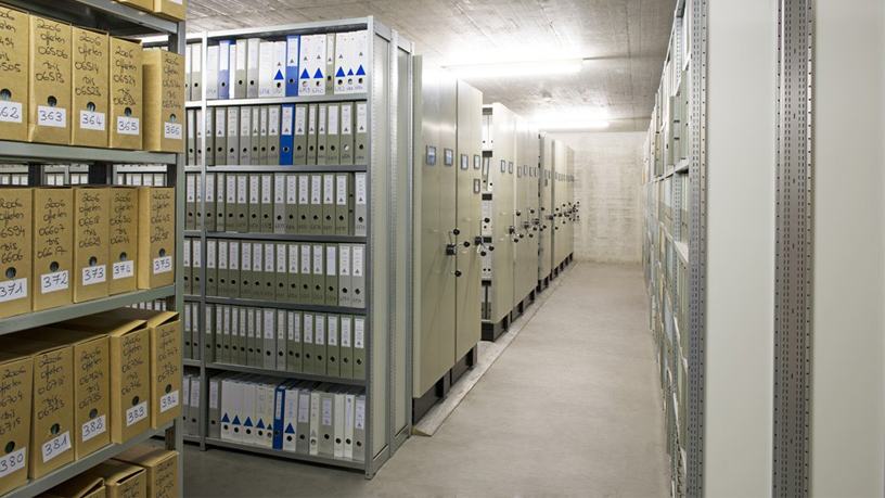 Archivraum mit Regalen voller Aktenordner und Kartons.