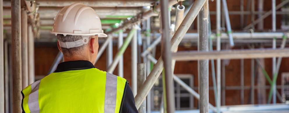 Arbeiter mit Schutzhelm und Warnweste auf einer Baustelle.