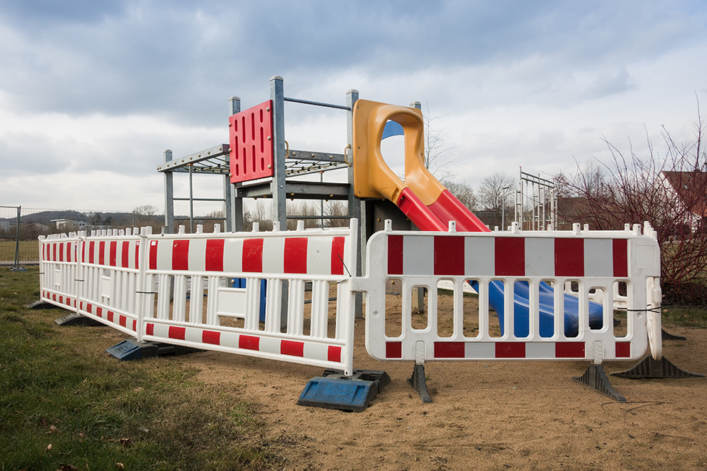 Absperrungen umgeben ein verwaistes Spielplatzgerät mit Rutsche.