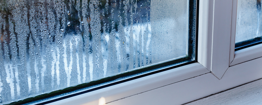 Nahaufnahme eines beschlagenen Fensters mit Wassertröpfchen auf der Scheibe.