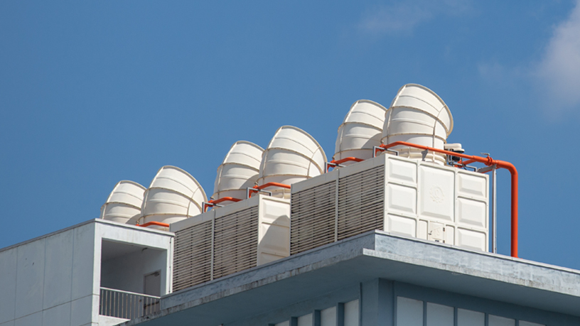 Kühltürme auf einem Gebäude unter blauem Himmel.