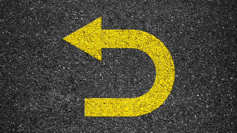 Gelber U-Turn-Pfeil auf Asphalt symbolisiert Publikationsrückrufe.