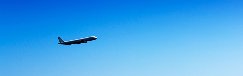 Flugzeug fliegt hoch am klaren blauen Himmel, symbolisiert Reisen und Technologie.
