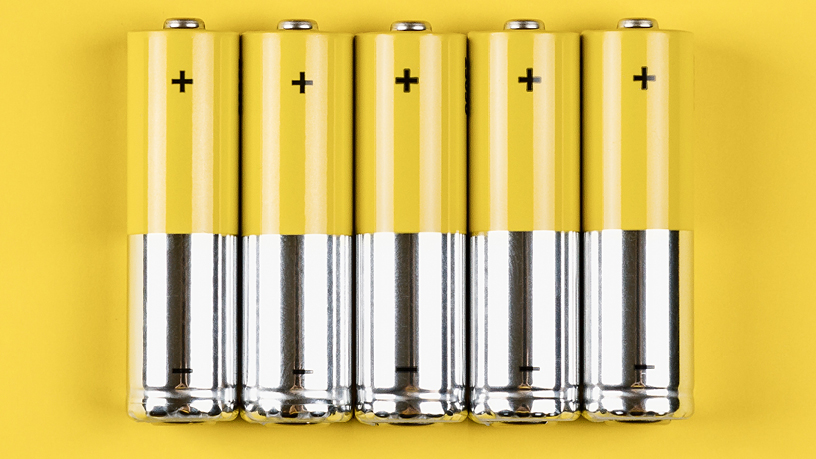 Fünf gelbe AA-Batterien in einer Reihe, zeigen Pluspol, symbolisieren gespeicherte Energie.