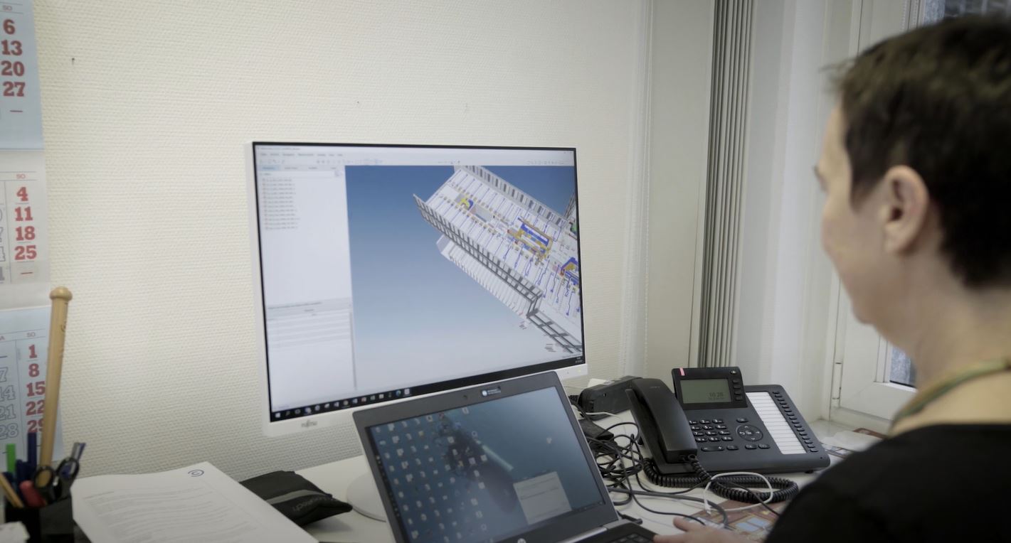 Person arbeitet an einem Computer, der ein Bauprojekt auf dem Bildschirm zeigt.