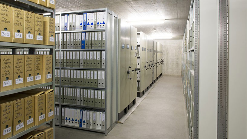 Archivraum mit Regalen voller Aktenordner und Kartons.