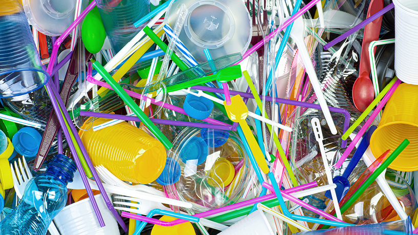 Buntes Plastikbesteck, Strohhalme und Flaschen liegen unordentlich übereinander 