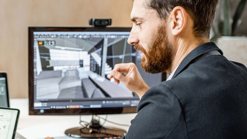 Person arbeitet am Computer an einem Architekturmodell.