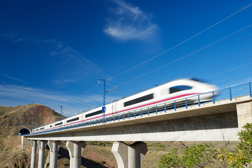 Hochgeschwindigkeitszug überquert eine Brücke vor Tunnel.