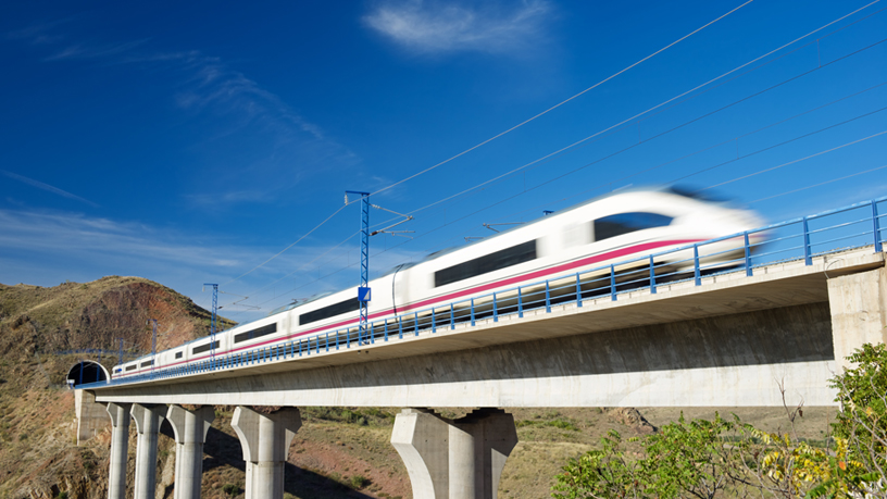 Hochgeschwindigkeitszug überquert eine Brücke vor Tunnel.