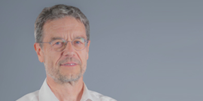 Matthias Springborn in weißem Hemd vor grauem Hintergrund.