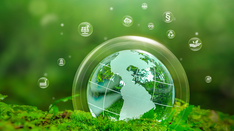 Gläserne Weltkugel auf grünem Hintergrund, umgeben von Symbolen für nachhaltige Entwicklung