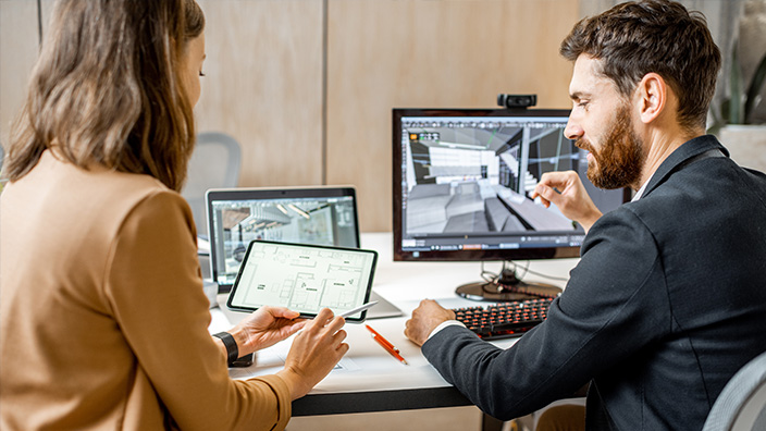  Zwei kreative Büroangestellte gestalten Innenarchitektur am Computer