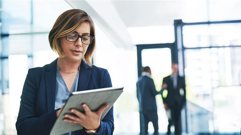 Managerin mit Laptop, im Hintergrund weitere Manager