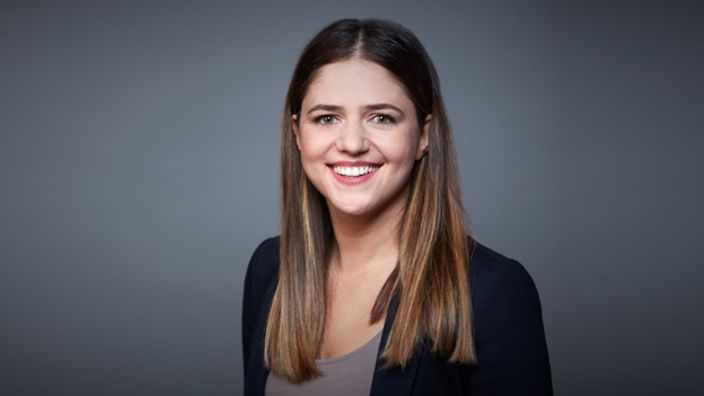 Filiz Elmas in einem schwarzen Blazer vor einem grauen Hintergrund.