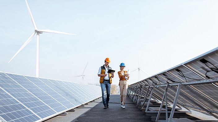 Ingenieure prüfen Solarpanels und Windräder.